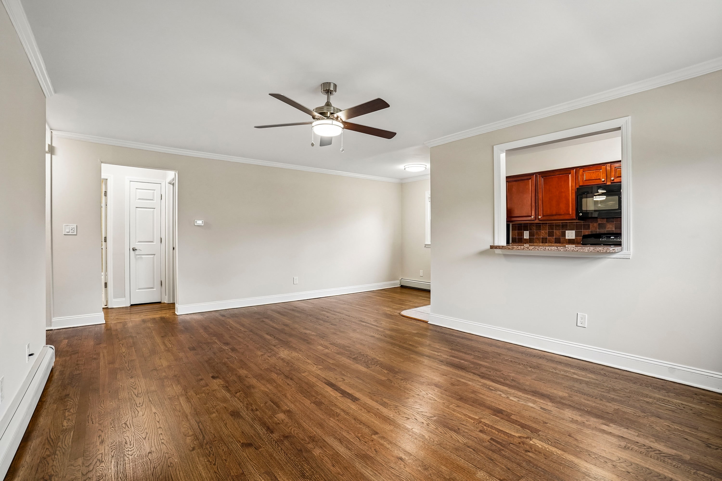 A room with a ceiling fan and wooden floors.